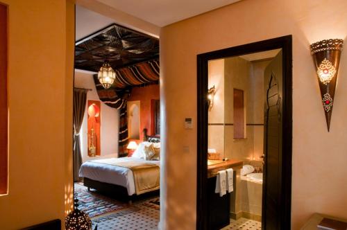 a bedroom with a bed and a bathroom with a mirror at Le Temple Des Arts in Ouarzazate