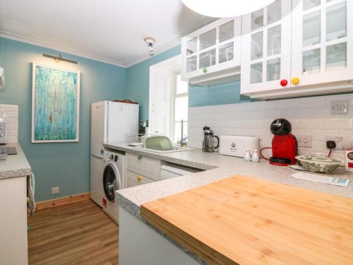 a kitchen with blue walls and white cabinets at Dookers' Hoose in Buckie