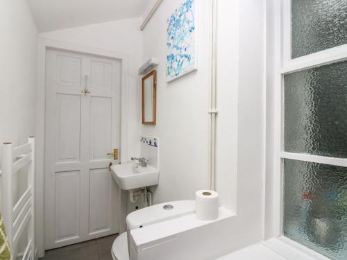a white bathroom with a toilet and a sink at Dookers' Hoose in Buckie