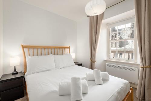 a bedroom with a bed with white sheets and a window at Castle Loft - 2 Bed - Central - Close to castle in St. Andrews