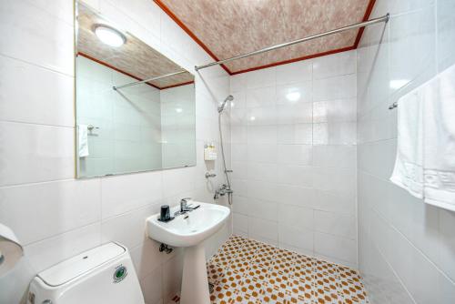 a bathroom with a sink and a toilet and a mirror at Charlie Hotel Jeju in Jeju