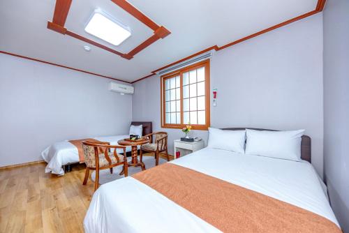 a bedroom with a bed and a table and a window at Charlie Hotel Jeju in Jeju