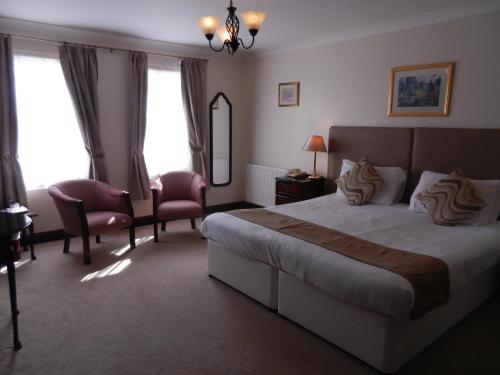 a bedroom with a bed and a chair and a mirror at Morangie Hotel Tain in Tain