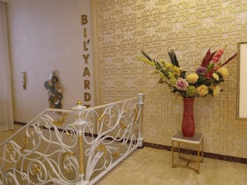 a vase of flowers on a table next to a staircase at Grand Holiday Hall in Pavlodar