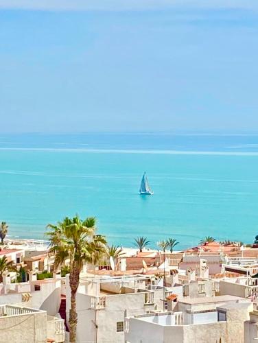a boat in the ocean with a sail boat in the water at Beautiful apartment near LaMata Beach with PANORAMA SEA view!!! in Torrevieja