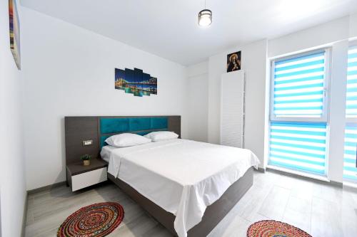 une chambre blanche avec un lit et une grande fenêtre dans l'établissement Turquoise Apartment Nord10 - Pool n Parking, à Mamaia