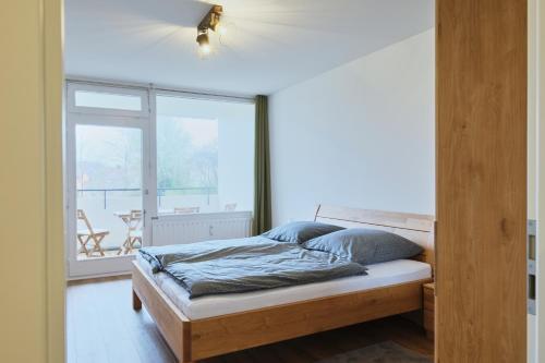 a bedroom with a bed and a large window at Topeingerichtete große 2-Zimmer Wohnung in Immenstaad am Bodensee