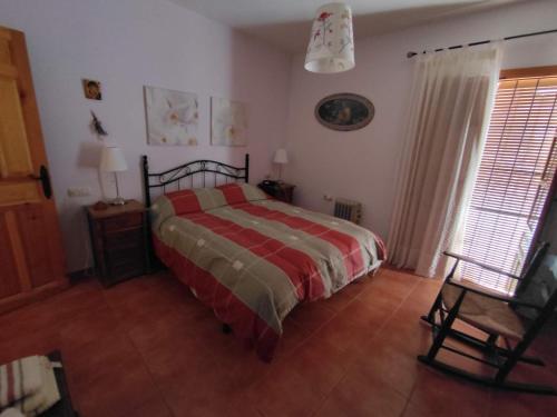 CASA PETRA : Bonita casa rural en Yunquera في Yunquera: غرفة نوم فيها سرير وكرسي