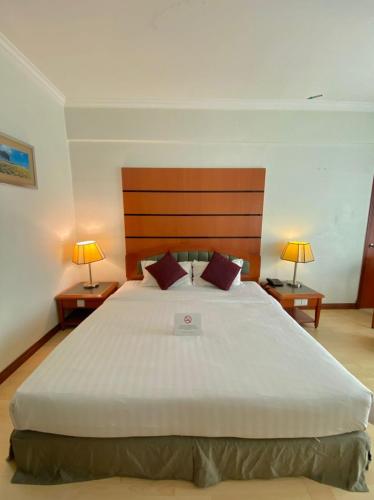 a bedroom with a large white bed with two lamps at Oriental Crystal Hotel in Kajang