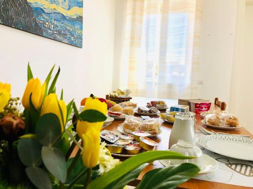 una mesa con platos de comida y flores. en Anthea B&B, en Ercolano