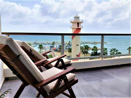 two chairs sitting on a balcony with a lighthouse at Apto Puerto Deportivo el Faro Marbella in Marbella