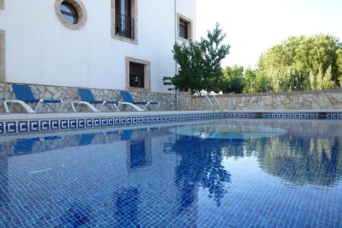 a swimming pool with chairs and a building at Lake View Villa in Iznájar