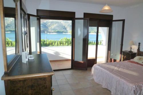 a bedroom with a bed and a view of the water at Lake View Villa in Iznájar