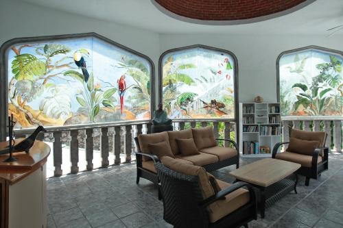 a living room with three large windows with paintings at Villa Bejar Tequesquitengo in Tequesquitengo