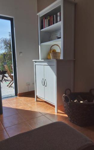 a white cabinet in a room with a book shelf at Casa do Brejão campo e praia in Odemira