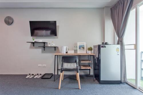 a kitchen with a table and a refrigerator and a desk at Cozzi by Grand Airport Resort in Lat Krabang