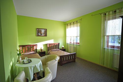 a green room with two beds and a table at Restauracja Zajazd Kasztelan in Krosno