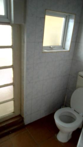 a bathroom with a white toilet and a window at Access Guest House in Summerstrand