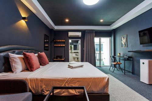 a bedroom with a large bed with blue walls at Cozzi by Grand Airport Resort in Lat Krabang