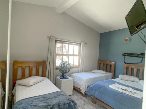 a bedroom with two beds and a window at Hotel dos Sonhos in São Thomé das Letras