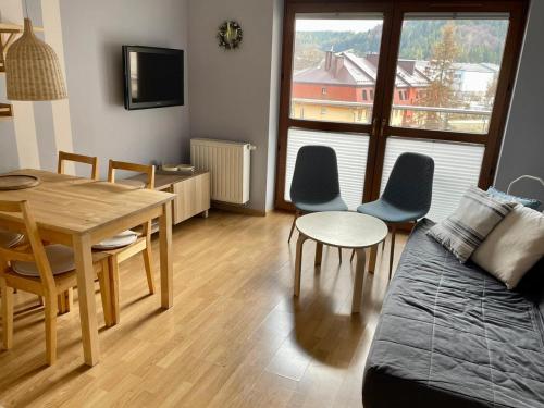 a living room with a table and chairs and a couch at Apartament Przytulny w Krynicy-Zdrój in Krynica Zdrój