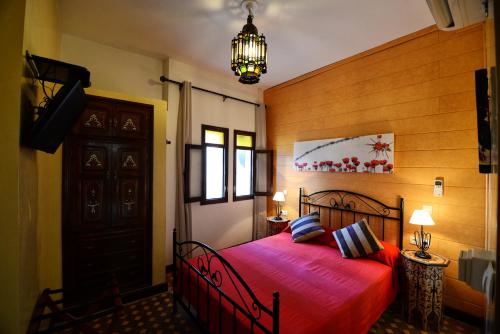 a bedroom with a red bed and a chandelier at Riad Assilah in Asilah