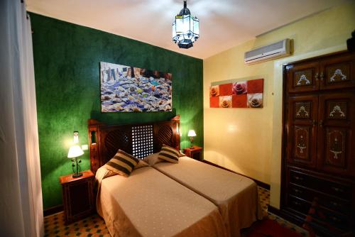 a bedroom with a bed and a painting on the wall at Riad Assilah in Asilah