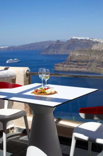 a table with a plate of food and a wine glass on it at Suites of the Gods Cave Spa Hotel in Megalochori