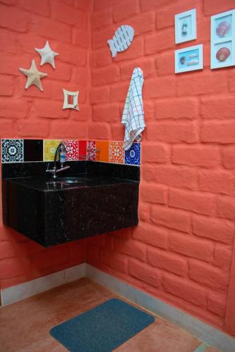 a bathroom with a red wall with a sink at Chácara Lápis Lazuli in Cavalcante