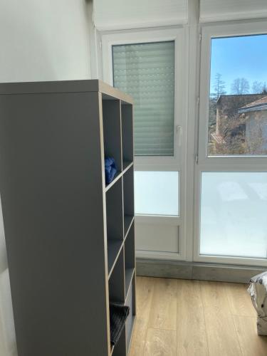 une étagère dans une chambre avec deux fenêtres dans l'établissement Appartement, à Beaumont