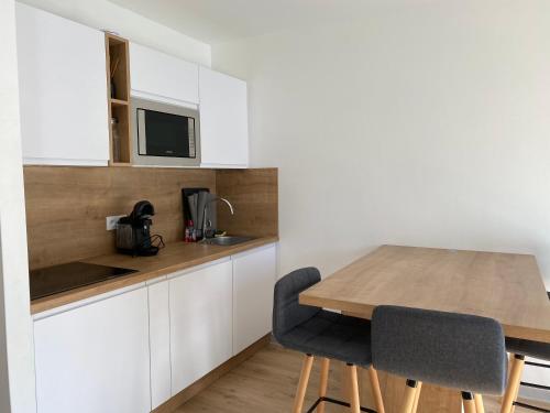 a kitchen with a wooden table and two chairs at Appartement calme in Beaumont