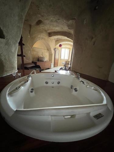 a large white bath tub in a stone room at Locus Amoenus in Matera