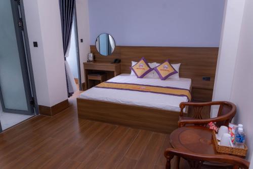 a bedroom with a bed and a mirror and a chair at Khách sạn Sớm Phú Quý - Ninh Thuận in Phan Rang