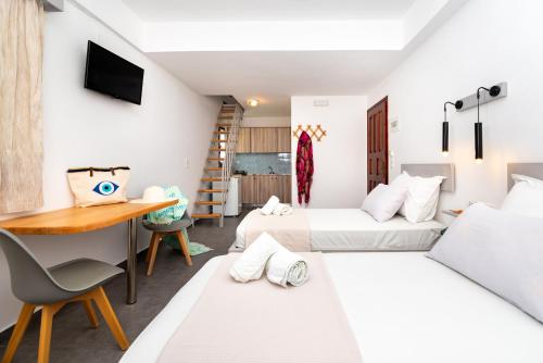 a room with two beds and a desk and a table at Marina's Studios in Perivolos