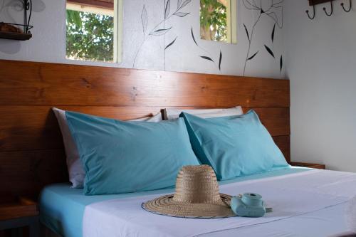 a straw hat sitting on a bed with blue pillows at Chácara Lápis Lazuli in Cavalcante