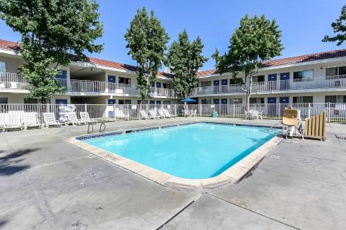 a swimming pool in front of a building with chairs at Motel 6-San Jose, CA - South in San Jose
