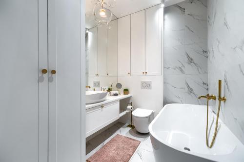 biała łazienka z wanną i umywalką w obiekcie Apartament Aura LUX w Szczecinie