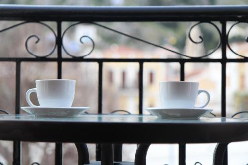 two coffee cups sitting on a table on a balcony at Main square apartment in Symi