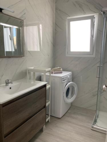 Un baño con lavadora y lavabo. en Apartament Roma V, Playa Gandia, en Gandía