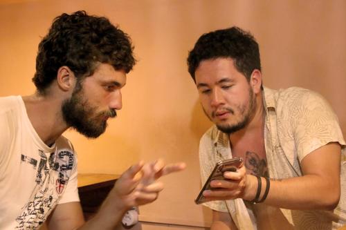 two men are looking at a cell phone at Santo Hostel in Porto Seguro