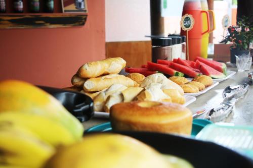 a table topped with plates of bread and pastries at Santo Hostel in Porto Seguro