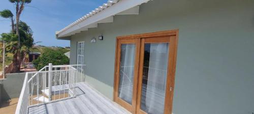 Casa con balcón con puerta de madera en Lovely Cozy Keito, en Palm-Eagle Beach