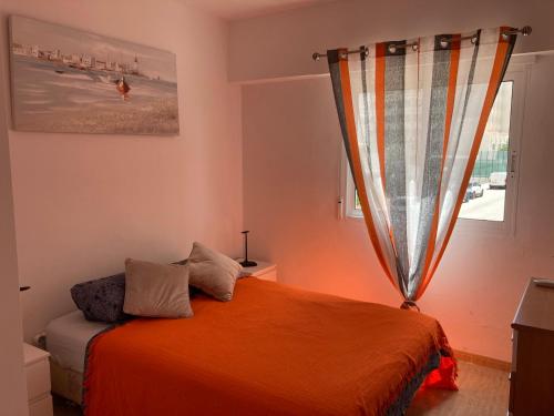 1 dormitorio con 1 cama con manta naranja y ventana en Apartament Roma V, Playa Gandia, en Gandía