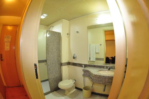 La salle de bains est pourvue de toilettes, d'un lavabo et d'un miroir. dans l'établissement Icaraí Praia Hotel, à Niterói