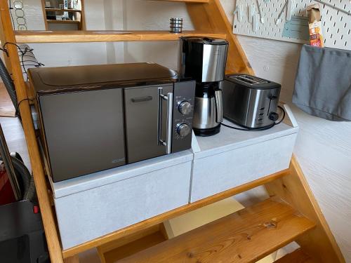 eine Küche mit einer Mikrowelle und einer Kaffeemaschine auf einem Regal in der Unterkunft Bi uns too Huus in Wilhelmshaven