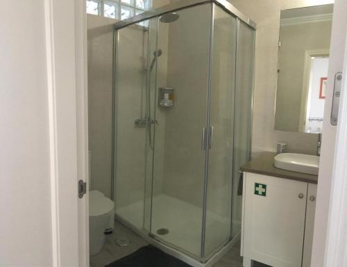 W łazience znajduje się szklana kabina prysznicowa i umywalka. w obiekcie Maré Alta w mieście Sines