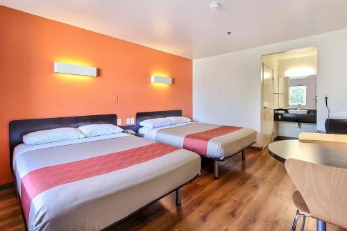 two beds in a room with orange walls and wooden floors at Motel 6-Sunnyvale, CA - North in Sunnyvale