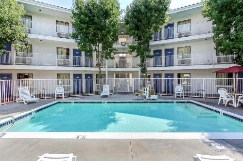 a pool in front of a building with chairs and a building at Motel 6-Sunnyvale, CA - North in Sunnyvale