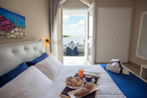 a bedroom with a white bed with a view of the ocean at Hotel Lo Scoglio in Porto Cesareo