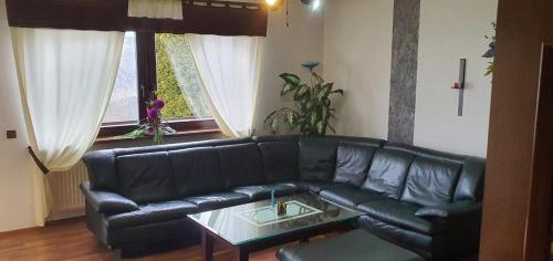 a black leather couch in a living room with a table at Haus Anicka zum Bömerwaldjeti in Aigen im Mühlkreis